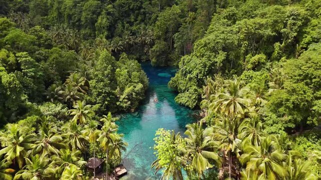 4k drone video flying back away from a small rowing boat in one of the clearest lakes in the world surrounded by trees and jungle landscapes. Paisupok Lake, Banggai Islands, Sulawesi Indonesia