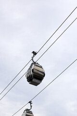 Modern cable cars gliding through the sky on wires under a cloudy sky in Japan.