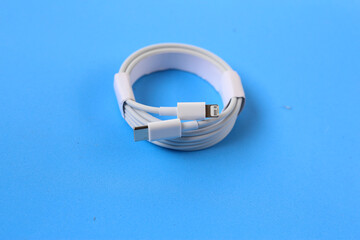 Cable with Type-C connector insulated, charging cable coiled on a blue background.