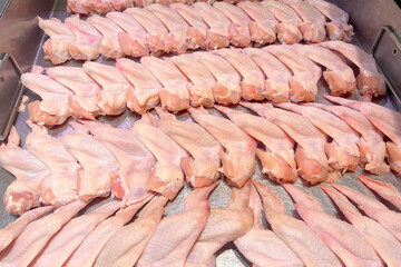 Fresh raw chicken wings neatly arranged in rows on a display tray
