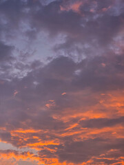 Dramatic evening sky with purple clouds and glowing orange sunset background