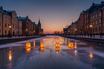 Fototapeta premium Winter evening in a historic waterfront town with illuminated numbers marking the new year 2026
