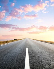 A wide-open highway stretches into the horizon beneath a vibrant sky at sunset, symbolizing freedom and adventure.