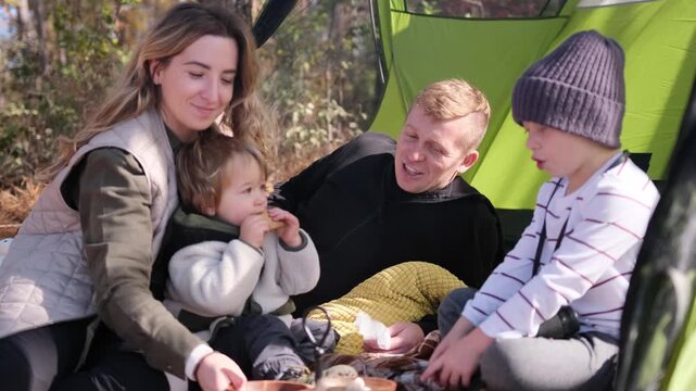 A happy family bonds while camping in a cozy outdoor setting, sharing joyful moments and discovering nature together