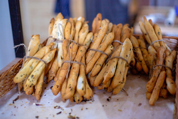 Breadsticks, grissini, grissino, sold in the form of bars. French sticks, salted with caraway, onion, anise from crispy, dry bread, selective focus. Grissini sold in the bakery. Craft baking.