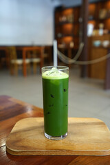Close up glass of Iced Matcha green tea on wooden tray table