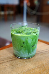 Close up glass of iced Matcha green tea with milk on wooden tray table