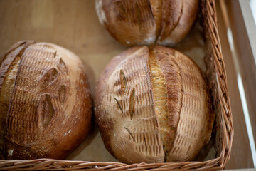 Craft sour homemade bread in a straw basket in a bakery. Sale of bread and bakery products. Sourdough bread. Healthy eating. Natural light, close-up.
