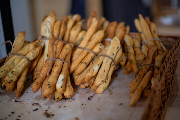 Breadsticks, grissini, grissino, sold in the form of bars. French sticks, salted with caraway, onion, anise from crispy, dry bread, selective focus. Grissini sold in the bakery. Craft baking.