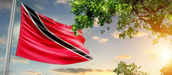 Trinidad and Tobago national flag waving in the sky behind the tree. The flag blow in beautiful...