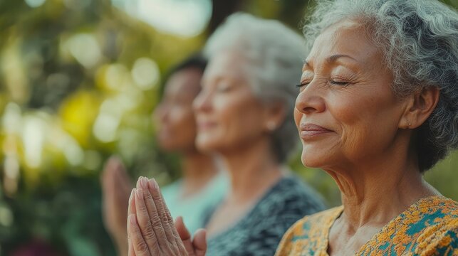 Multiethnic senior female friends praying and meditating together in a gym class. Happy elderly multiracial women practicing yoga and breathing exercises. Promoting fitness - mental, Generative AI