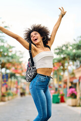 Fototapeta premium Portrait of a young woman girl walking in the city street, jumping and having fun.
