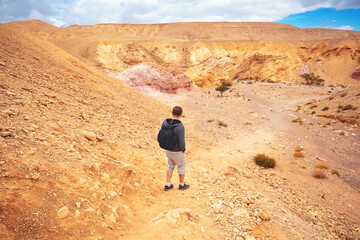 Fototapeta premium Young man walking in the desert. Road to Red Canyon in the Negev Desert, Israel