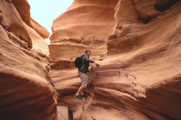 The young man is climbing a canyon in a dry riverbed in the desert. Red Canyon in the Negev desert, Israel