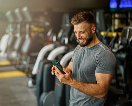Portrait of a young man using a phone ant exting taking a break exercising in a gym, running using  thereadmill machine equipment, healthy lifestyle and cardio exercise at fitness club concepts