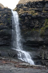 Waterfall cascading over dark rocks in the Faroe Islands
