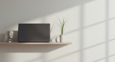 Fototapeta premium Minimalist workspace with a sleek closed laptop, potted plant, and modern abstract sculpture on light wooden shelf with soft natural shadows, emphasizing simplicity and elegance