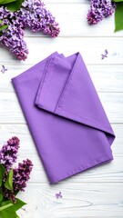 Purple napkin on white wooden background with lilac flowers