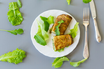 Appetizing omelette with greens and arugula on a white plate
