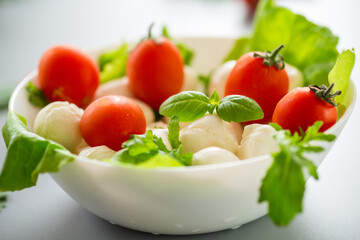 mini mozzarella in white bowl with herbs and cherry tomatoes