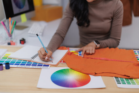 Fashion designer working with colour swatches and notebook taking notes choosing colour palette