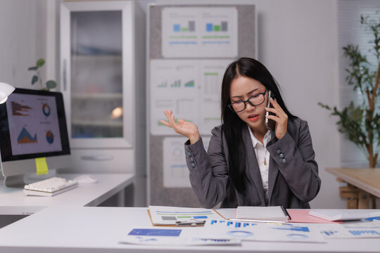 Stressed businesswoman having phone call discussing negative financial report in office - Powered by Adobe