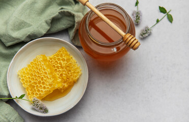 Honeycomb and honey jar with wooden dipper on marble table