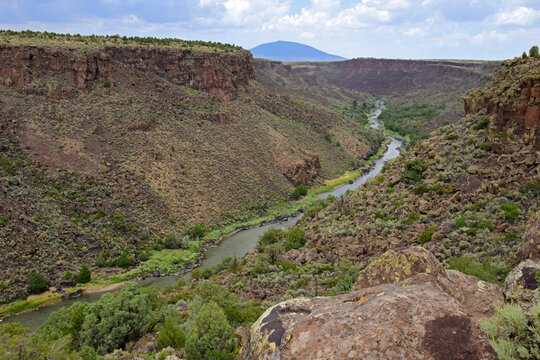 looking  out at  mountains  and  the  rio grande river from  a steep overlook in the rio grande del norte national monument  near taos, new mexico, on a  summer day 