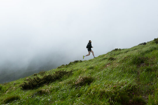 Bright collage of male athlete running uphill on misty green mountain slope. Concept of endurance branding, eco trail ads, motivational posters, wellness lifestyle content.