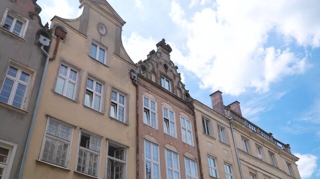 Row of traditional gabled houses in Gdansk Old Town under sunny blue sky.