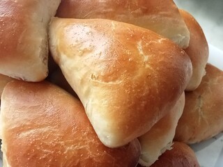 Several golden brown, baked, triangle-shaped pies piled high.