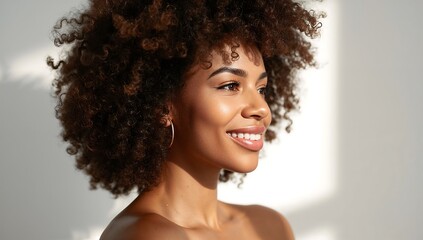 Close up of a smiling african american woman with curly hair and hoop earrings against a white background