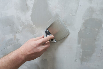 Plasterer plastering a wall with a spatula, closeup