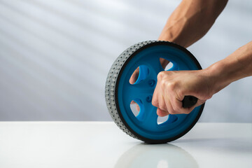 Strong Hands Gripping an Abs Wheel Roller for Core Workout with copy space
