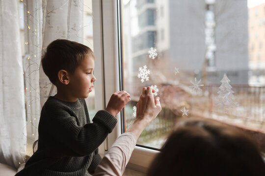 Father and son decorating window with snowflake ornaments for Christmas