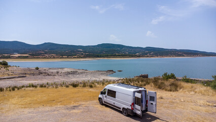 Obraz premium Drone view of a camper van on a lake on the island of Sardinia. Lake Coghinas, travel. Travel, lifestyle, camper world