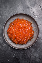 Luxurious red caviar, glistening pearls of flavor, perfect for elevating any gourmet dish or appetizer. black background. top view