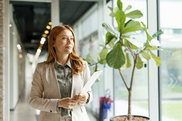 Confident businesswoman holding documents in modern office interior