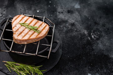 Juicy grilled tuna steak, perfectly seared with a smoky flavor, ideal for seafood lovers and gourmet dishes. black background. top view
