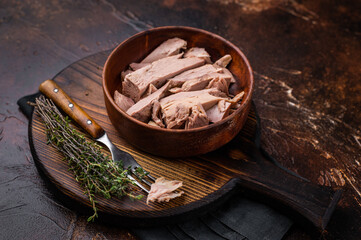 Sustainable tinned tuna fillet in a wooden bowl, promoting eco friendly eating without sacrificing taste. brown background. top view