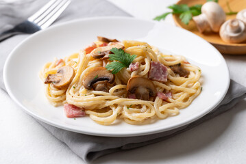 Spaghetti carbonara with ham, bacon and champignon mushroom on white plate, Italian food