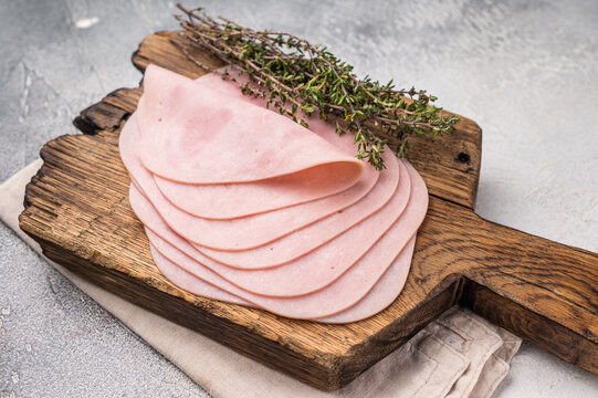Delicious slices of cured ham on a wooden platter, ideal for entertaining and adding flavor to your dishes. white background. top view