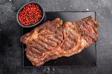 Roasted Chuck eye roll steak, marbled beef meat on a board. black background. top view