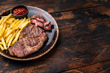 Dinner with grilled Chuck eye roll steak and french fry on a plate. wooden background. top view
