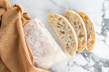Italian baked and sliced ciabatta bread on a marble table. marble background. top view