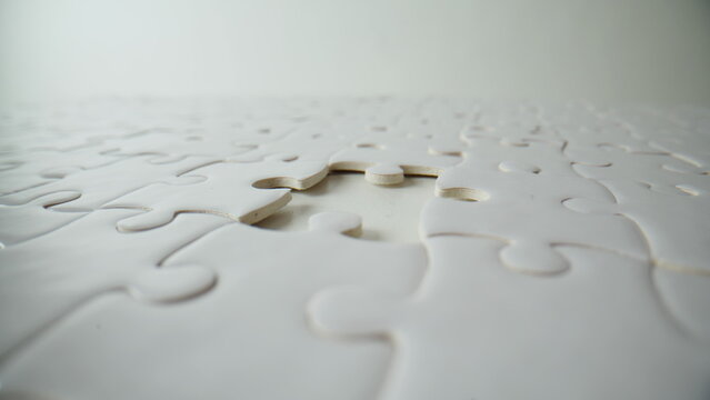 Fingers placing last puzzle finishing closeup. Unknown person assembling jigsaw