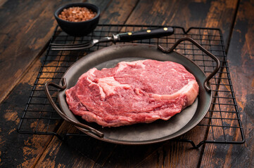 Prime Rib eye steak in a tray, raw dry aged beef meat on wooden background. top view