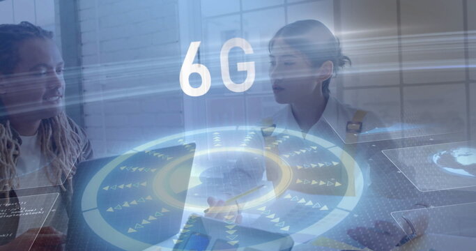 Collaborating professionals inputting on laptop and tablet in office with holographic 6G overlay