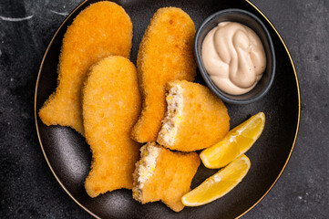 Crispy fried cod Fish sticks on plate. black background. top view