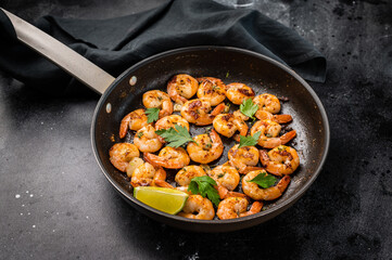 Fried Shrimps Prawns with garlic and butter in a skillet. Black background. Top view